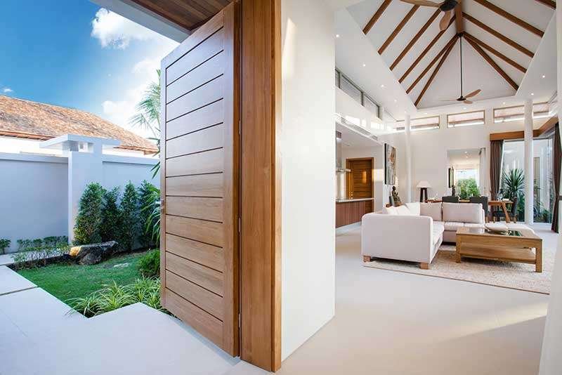 Porte d'entrée sur mesure en bois exotique, ouverte sur un jardin luxuriant