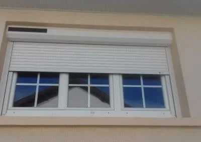 Volet roulant solaire blanc sur fenêtre trois vantaux