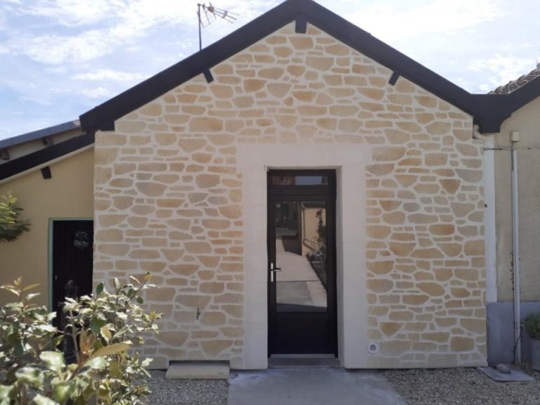 Porte d'entrée vitrée pvc noire sur façade en pierres blanches.